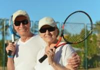 Happy elderly couple with tennis racket in hand